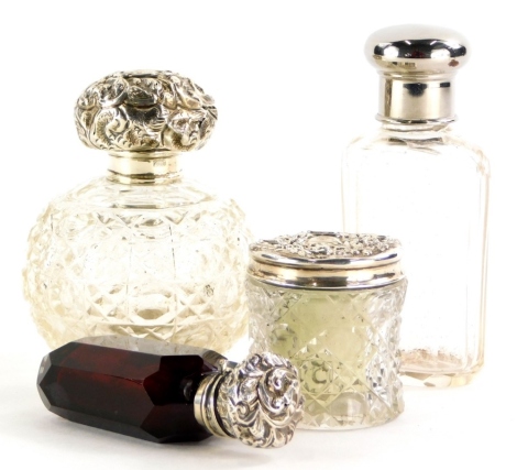 A quantity of small silver mounted items, to include a scent bottle with an embossed cover (stopper AF), two cut glass jars, each with embossed lid and a glass jar with silver plated lid. (4)