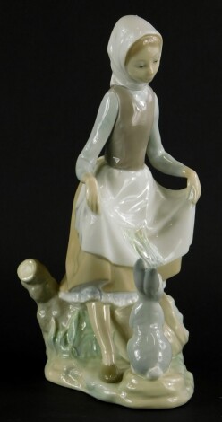 A Lladro porcelain figure group, of a young lady with a rabbit, printed marks in blue to underside, 22cm high.