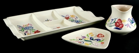 Three items of Poole pottery, to include a rectangular hors d'oeuvres tray, a tapering rectangular dish and a jug, each painted with flowers, leaves, etc.