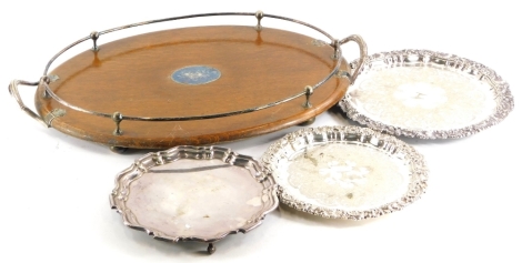 A late 19th/early 20thC oak oval two handled galleried tray, with silver plated mounts, 62cm wide, and three silver plated salvers.