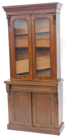 A Victorian walnut, pine and oak bookcase, the top with a moulded cornice with two glazed doors enclosing adjustable shelves, the base with a frieze drawer and two panelled doors on a plinth, 200cm high, 89cm wide. (AF)