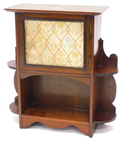 An Edwardian mahogany small cupboard, with a moulded cornice, above a glazed door, inset with embroidered panel, flanked by shaped recesses, above a further recess on a plinth, (AF), 68cm high, 65cm wide.