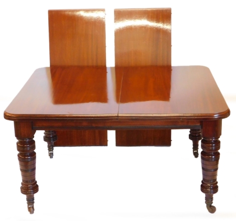 A late Victorian mahogany extending dining table, the rectangular top with a moulded edge above a plain frieze with ring turned legs and castors, two associated loose leaves and winding mechanism with handle, 75cm high, the top 235cm x 115cm extended.