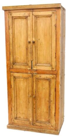 A pine cupboard, with a moulded cornice above two pairs of panelled doors, on a plinth, lacking back, 195cm high, 86cm wide.