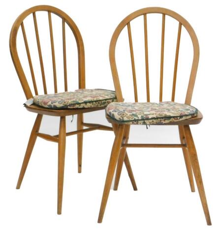 A pair of Ercol stick back kitchen chairs, each with a solid seat on turned tapering legs.