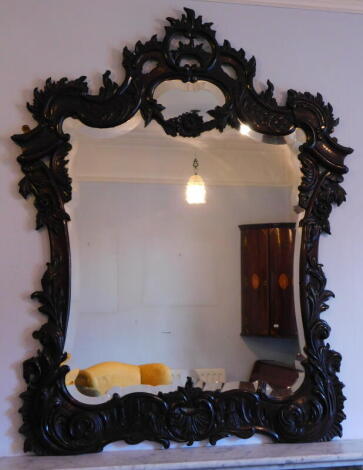 A 19thC carved rococo wall mirror, with c and s shaped scrolls, around a bevelled plate, 135cm high, 110cm wide.