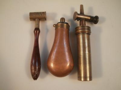 An antique cylindrical brass powder flask with spring loaded action