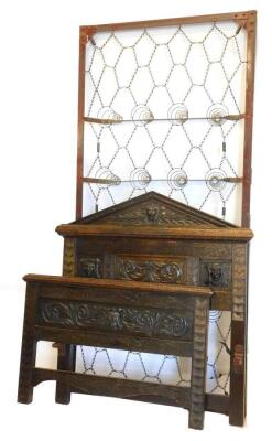 An Edwardian oak single bedstead, with carved mask and demi-lune decoration.