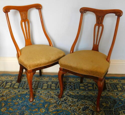 A pair of late Victorian walnut bedroom chairs, with down swept arms and cabriole legs.