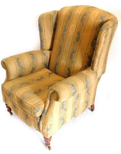A Victorian wingback armchair, with turned legs and brass castors.