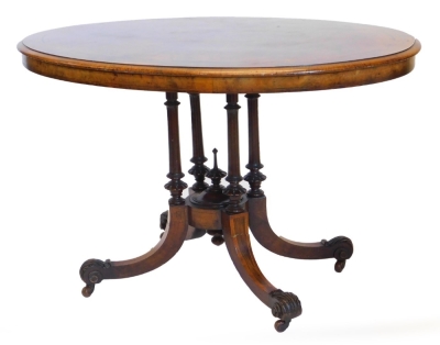 A Victorian walnut and marquetry loo table, with oval top cross banded with amboyna and ebonised panels, turned supports and four sabre legs with acanthus scroll cap feet and castors, 115cm x 76cm.