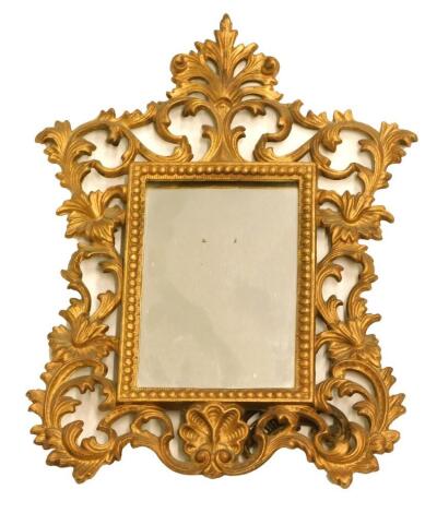 An early 20thC gilt metal rococo design mirror, of shaped form with a pierced scroll and floral outline and bead inner frame, with plain glass, on articulated easel back, 30cm high, 22cm wide, 3cm deep.