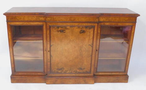 A Victorian figured and burr walnut veneered breakfront credenza, with mahogany cross banded and string inlaid top, Arabesque marquetry frieze, over a central panelled door with quarter veneers flanked by glazed cross banding glazed doors and plinth base,