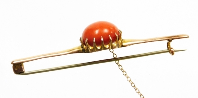 A 9ct gold coral set bar brooch, the large circular coral cabochon in a claw setting, 1.6mm wide, 9.2mm deep, the coral with pierced back, on a plain design brooch, on a steel pin back and safety chain, 7cm wide, 8.7g all in, boxed. - 2