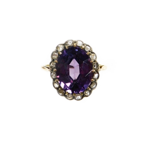 A diamond and alexandrite cluster dress ring, set with oval alexandrite ,surrounded by tiny diamond chips, in a rubover setting, on pierced basket and splayed shoulders, yellow metal unmarked, ring size N½, 3.8g all in.