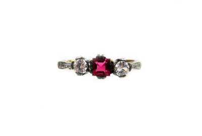 A Victorian three stone dress ring, set with garnet and two imitation diamonds, in a silver setting on a yellow metal band, unmarked, ring size L½, 1.6g all in.