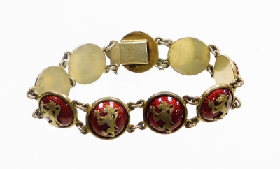 A Continental enamelled cabochon link bracelet, the bracelet formed of various circular links, each raised and finished in red enamel and applied with a rampant lion motif, with safety chain, the clasp stamped O.H.R, white metal marked 830S, approx 20cm l - 2