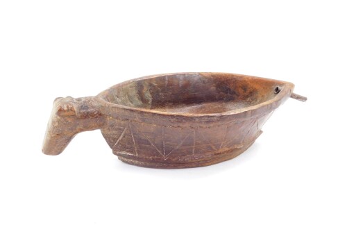 A heavily carved treen vessel, possibly Norwegian, with shaped animal handle and eliptical shaped body, naively carved with a geometric pattern to the exterior, 22cm wide.