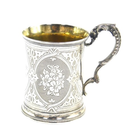 A Victorian silver tankard, with foliate scroll handle, engraved with panels of flowers, central reserve engraved G A S Savage., 26th April 1887., Richards & Brown, London 1867, 3.98oz.