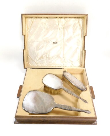 A George V silver backed four piece dressing table set, with engine turned decoration, cased, comprising hair and clothes brushes, hand mirror and a comb, Birmingham 1913.