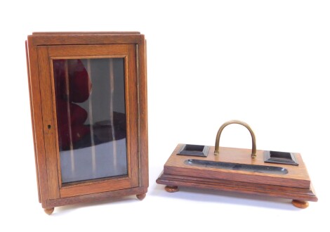 An early 20thC oak cased invoice cabinet, the glazed door opening to reveal four compartments, raised on brass ball feet, 37cm high, 22.5cm wide, 26.5cm deep., together with a Victorian oak and ebonised desk stand, 34.5cm wide. (2)