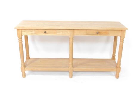 A 20thC light oak side table, the rectangular moulded top raised above two frieze drawers, on turned supports, joined by a plain under tier, terminating on turned feet, 82cm high, 146cm wide, 41cm deep.