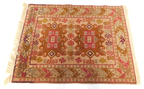 A 20thC Turkish style rug, set with two bold floral central emblems, the outer field with a floral border, on cream ground, 109cm x 87cm.