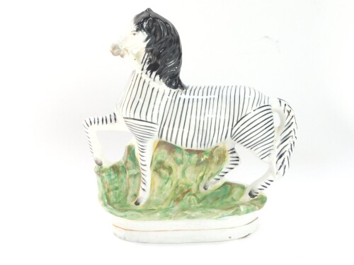 A Staffordshire late 19thC pottery flat back figure of a zebra, modelled in standing pose, facing left, 23cm high.