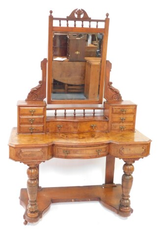 A late Victorian walnut mirror back dressing table, the shaped glass flanked by acanthus leaf and scroll supports, above a serpentine drawer, flanked by six further drawers, with an inverted subsection, raised on heavily carved legs on a platform base ter