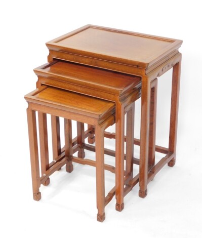 A nest of three Chinese hardwood tables, of rectangular form, with frieze carving on shaped legs joined by shaped horizontal stretchers, the largest 67cm high, 55cm wide, 38cm deep.