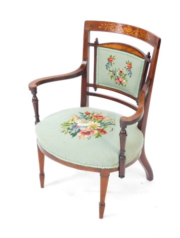 An Edwardian mahogany and boxwood occasional chair, with shaped cresting rail, inset with urns, flowers and scrolls, with an over stuffed back and seat in petit point material, on front square tapering legs terminating in spade feet, with shaped arms and 