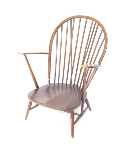 An Ercol dark elm hoop back low armchair, with plain cylindrical spindles, shaped arms and seat on turned legs joined by an H stretcher, 92cm high.