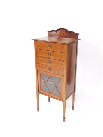 An Edwardian mahogany music cabinet, with arched top raised above four drawers with articulated front of a glass panelled cupboard revealing shelf beneath on square tapering leaves, terminating in spade feet, 119cm high, 53cm wide, 33cm deep.