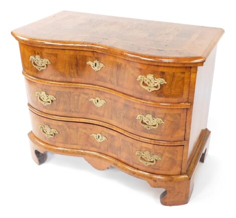 An early 19thC Dutch walnut serpentine chest, with deep cross banded and moulded top over three drawers, with brass pressed loop handles and escutcheons, on bracket feet, 76cm high, 96cm wide, 52cm deep.