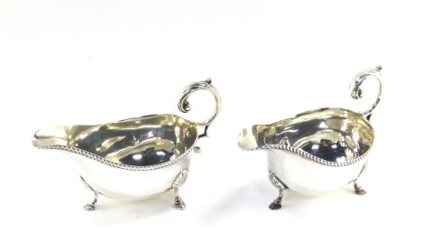 A pair of Edward VII silver sauce boats, with leaf scroll handles, gadrooned rims and raised on three hoof feet, London 1908, 10.95oz.