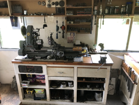 A Myford lathe workstation, comprising single phase bench top lathe, and the illustrated tooling, including drills, reamers, threaded mandrill, slot mills, dial gauges, etc. (on upper shelves)., and the base cabinet, having drawers of files, hammers, scre