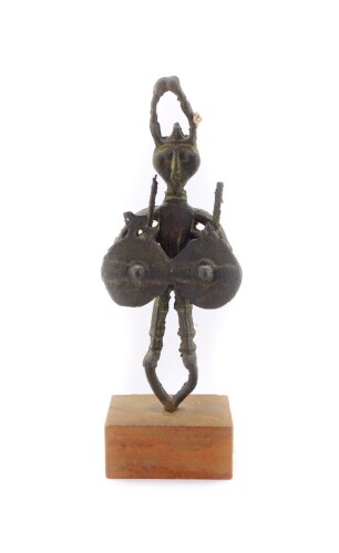 An ethnographic cast iron figure of a warrior, modelled with an elaborate headdress and conjoined double circular shield, raised on a rectangular wooden block base, 37cm high.
