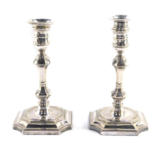 A pair of George I style silver plated candlesticks, each with removable pressed sconces, urn finials, inverted stems, and octagonal platform bases, marked Goldsmiths & Silversmiths Company, , 21cm high.