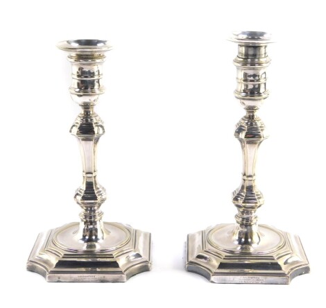 A pair of George I style silver plated candlesticks, each with removable pressed sconces, urn finials, inverted stems, and octagonal platform bases, marked Goldsmiths & Silversmiths Company, , 21cm high.