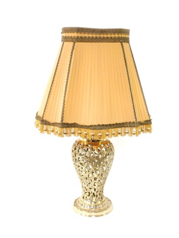 A brass table lamp, of pierced baluster form, decorated with scrolling leaves, with a shade, 76cm high.