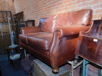 A brown leather two seater sofa, with studded arms, 165cm long.