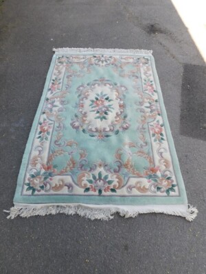 A Chinese wool rug, green ground with floral design, 210cm x 127cm.