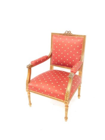 A gilt wood armchair, with ribbon back and heavily carved frame, with overstuffed back, arms and deep seat in decorative star material on red ground, with acanthus carved scroll arms and further mouldings and roundels, on turned reeded legs, 107cm high.