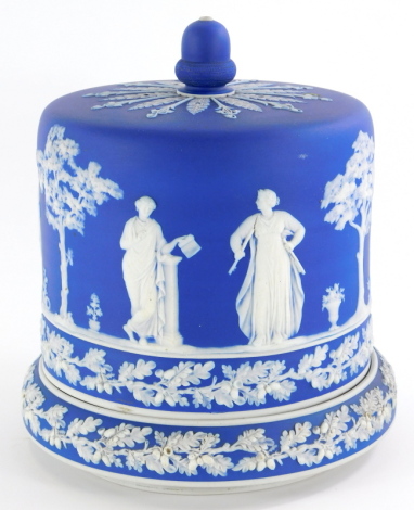 An early 20thC blue Jasperware cheese dome and base, decorated with an acorn finial and Neoclassical figures, probably Wedgwood, unmarked, 26cm high.