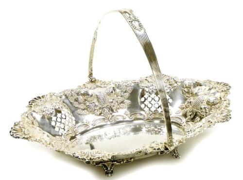 A Victorian silver fruit basket, by Thomas Latham and Earnest Morton, with a shell and scroll outline, heavily repoussé decorated with fruits, with plain oval centre and swing handle, on quadruple scroll feet, Birmingham 1899, 29cm long, 13oz.