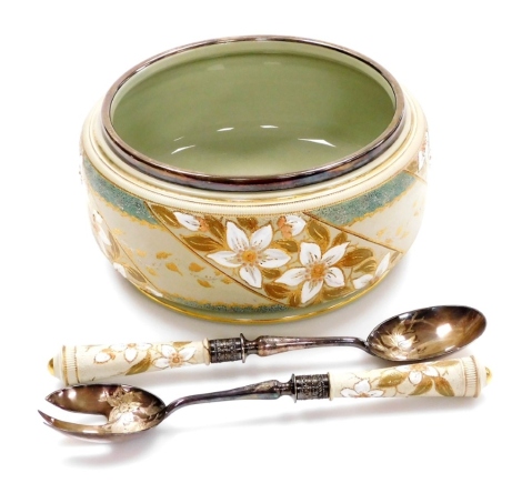 An Edwardian George Jones green stoneware salad bowl and matching servers, decorated with flowers and picked out in gilt, with a silver plated rim, together with a pair of matching salad servers with silver plated tops each florally embossed, 23cm diamete