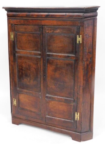 An early 19thC oak freestanding corner cupboard, with double panel doors, the plain interior set with drawers beneath, on bracket feet, 120cm high, 90cm wide, 50cm deep.