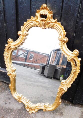 A modern gilt framed oval wall mirror, with carved frieze, 90cm high, 55cm wide.