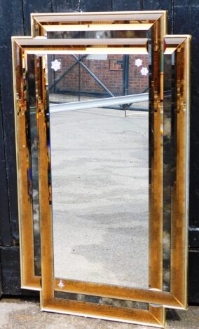 A modern art glass wall mirror, with a gilt applied surround, with two colour glass banded surround, in copper type colour, in the Art Deco style, 124cm high, 74cm wide.