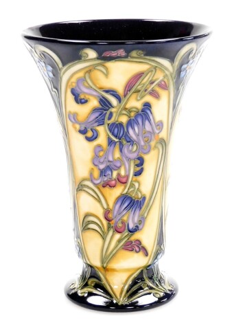 A Moorcroft floral flared vase, depicting flowers on a dark blue and yellow ground with green Moorcroft stamp to underside, dated 2011, with marked red dot, 15.5cm high.